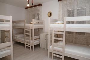 Hostel Korcula في كورتْشولا: غرفة بها العديد من الأسرّة ذات الطابقين الأبيض