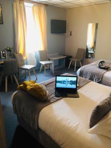 a hotel room with a laptop on top of a bed at Logis Hôtel Restaurant Azalées in Tournon-sur-Rhône