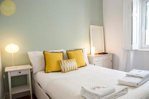 Un dormitorio con una cama con almohadas amarillas y una ventana en PAZ 38 - Premium Location en Lisboa