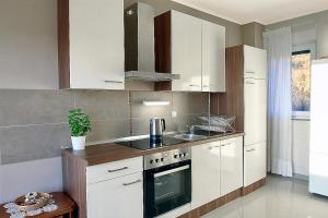a kitchen with white cabinets and a stove at Bayview Apartment in Selce