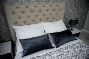 Una cama con almohadas blancas y negras. en Glamour Apartments en Piła