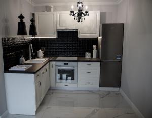 kuchnia z białymi szafkami i czarną lodówką w obiekcie Glamour Apartments w mieście Piła
