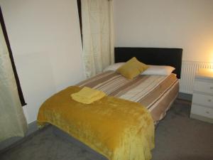 een slaapkamer met een bed met een gele deken erop bij Villa Anson in Manchester