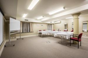 a conference room with white tables and red chairs at Launceston Central Apartment Hotel Official in Launceston