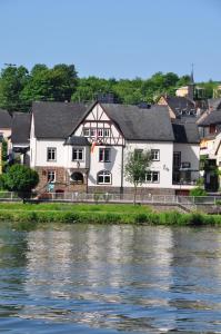 duży biały budynek obok rzeki w obiekcie Mosel-Landhaus B&B w mieście Briedern