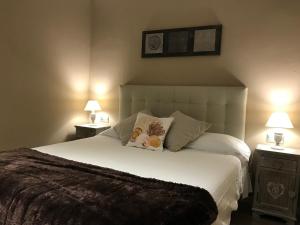 um quarto com uma grande cama branca com duas mesas de cabeceira em La Magnòlia i L´Alzina em Blanes