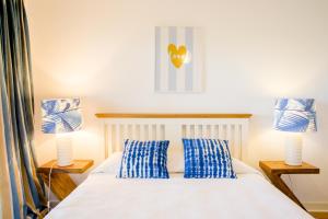 a bedroom with a white bed with blue pillows at Loving Tróia in Troia