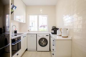 a white kitchen with a washing machine and a window at Loving Tróia in Troia +31 photos