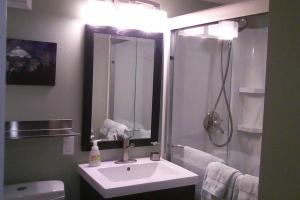 a bathroom with a sink and a shower with a mirror at Boutique Style Apartment in the heart of SE in Portland
