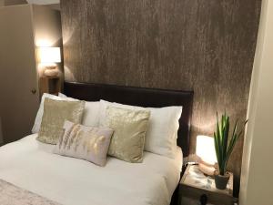 um quarto com uma cama com lençóis brancos e almofadas em The Windsor Carlton em Blackpool