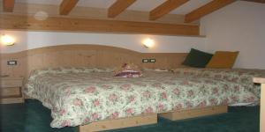 a bedroom with a large bed with a floral bedspread at DOLOMITI appart&rooms in Varena