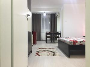 a bedroom with a bed and a table and a rug at Faleza Apartment in Galaţi