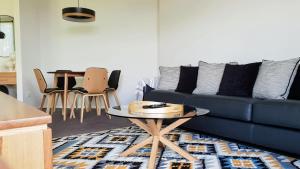a living room with a blue couch and a table at Number 9 Leisure Stay in Port Campbell