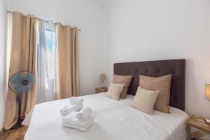 a white bed with a white comforter and pillows at Faro Cosy Guesthouse in Faro