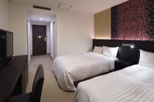 a hotel room with two beds and a television at Hotel Mets Nagaoka in Nagaoka