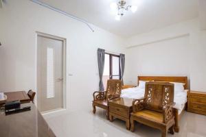 a bedroom with two chairs and a bed and a window at 宜蘭樸實園民宿 in Jiaoxi