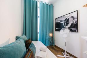 Faro Cosy Guesthouse في فارو: غرفة معيشة مع ستائر زرقاء وأريكة زرقاء