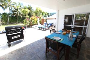eine Terrasse mit einem Tisch und einem Grill in der Unterkunft White House Apartments in Rarotonga