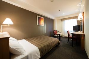 Habitación de hotel con cama, escritorio y TV. en Ark Hotel Osaka Shinsaibashi -ROUTE INN HOTELS-, en Osaka