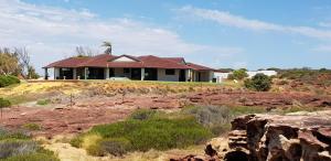 a house with a palm tree on top of a hill at Kalbarri Red Bluff Tourist Park in Kalbarri