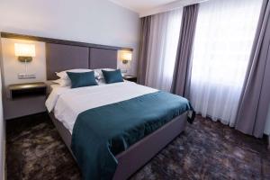 a hotel room with a large bed with blue pillows at Best Western PLUS Premium Inn in Sunny Beach