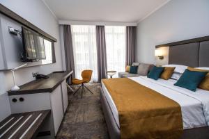 a hotel room with a large bed and a couch at Best Western PLUS Premium Inn in Sunny Beach