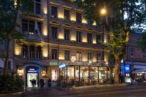 un bâtiment avec un magasin devant lui la nuit dans l'établissement Hotel Imperiale by OMNIA hotels, à Rome