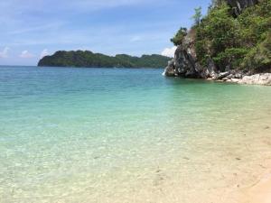 een strand met helder water en bomen op de achtergrond bij Se San Beach Resort-Isla de Gigantes in Carles