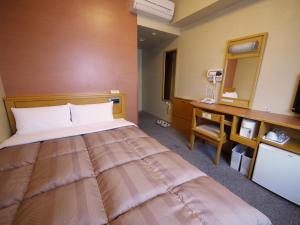 山形市にあるホテルルートイン　山形駅前の大きなベッドとデスクが備わるホテルルームです。