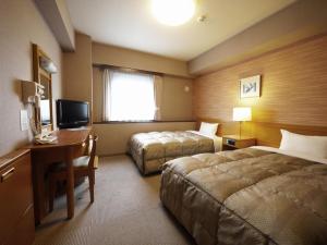 a hotel room with two beds and a desk and a television at Hotel Route-Inn Yamagata Ekimae in Yamagata