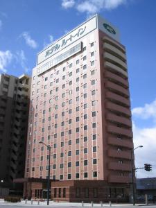 um grande edifício cor-de-rosa com um cartaz. em Hotel Route-Inn Yamagata Ekimae em Yamagata