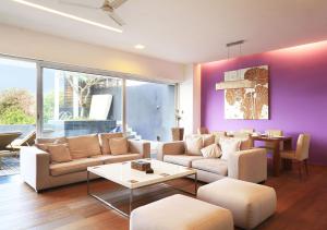 a living room with white furniture and purple walls at Bay Terraces Beach View - Vasco Da Gama by StayVista in Marmagao