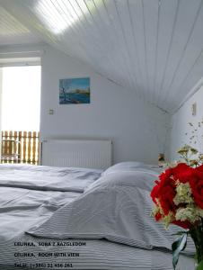 Un dormitorio blanco con una cama con un jarrón de flores rojas en CELINKA rooms en Raka