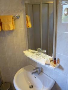 a bathroom with a sink and a shower with a mirror at Pension Brönimann in Ossiach