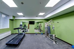 einen Fitnessraum mit grünen Wänden und Laufbändern in der Unterkunft London Boutique Hotel in Chişinău