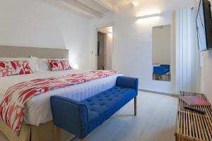 a bedroom with a large bed and a blue bench at Le Maestranze Deluxe Rooms in Sciacca