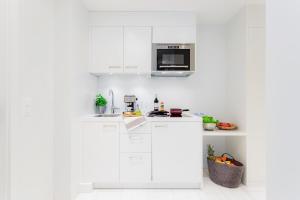 cocina con armarios blancos y microondas en VISIONAPARTMENTS Baarerstrasse - contactless check-in en Zug