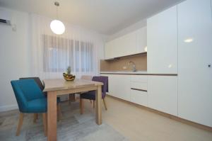 a kitchen with a wooden table and blue chairs at Corso Levante Luxury Suites in Petrovac na Moru