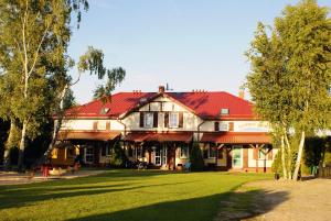 a large house with a red roof on a green field at Barwy Morza - domki in Rowy