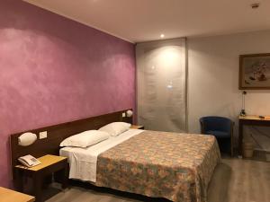 une chambre d'hôtel avec un lit et un mur violet dans l'établissement Hotel San Giorgio, à Udine