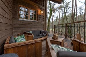 eine abgeschirmte Veranda mit Sofas und Tischen auf einer Terrasse in der Unterkunft Boomhut Drouwenerzand in Drouwen