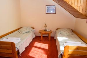 two beds in a small room with a table at Hotel Fortuna in Dávod