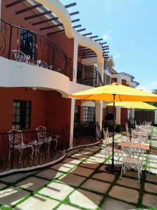 Machakos Suites Luxury Hotel في Machakos: فناء به طاولات ومظلات على مبنى