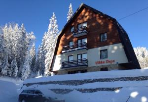 a building in the snow with a car in front at Apartments Villa Deja in Jahorina