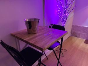 einen Holztisch mit zwei Stühlen und einem lila Licht in der Unterkunft Le Paradis Perdu in Rouen