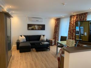 ein Wohnzimmer mit Couch und Flachbildfernseher in der Unterkunft Gästehaus Alpinia in Berlin