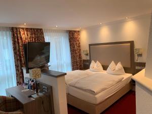 ein Hotelzimmer mit einem Bett und einem Flachbildfernseher in der Unterkunft Gästehaus Alpinia in Berlin