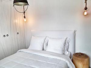 a white bed with white pillows and a table at Villa Arion in Batsi
