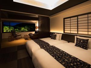 two beds in a hotel room with a window at barhotel Hakone Kazan in Hakone