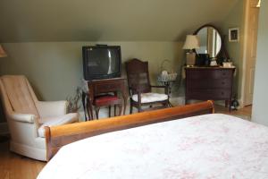 a bedroom with a bed and a tv and chairs at Lynwood Inn in Baddeck